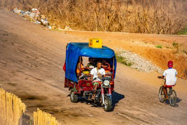 Antsirabe, Madagaskar 19 Ekim 2023. Morondava 'dan Antsirabe' ye giden yol Madagaskar 'ın ortasındaki boş otlaklar ve köyden geçiyor. Yolcuları olan Tuktuk.