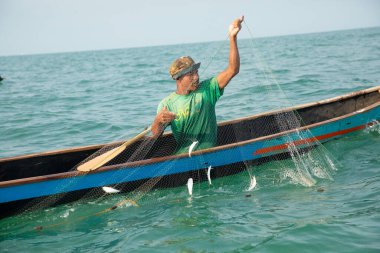 Morondava, Madagaskar. 18 Ekim 2023. Ev yapımı ahşap pirogue teknesindeki kötü niyetli balıkçı ağla balık yakalar. seçici odak, okyanusun yakın görüntüsü