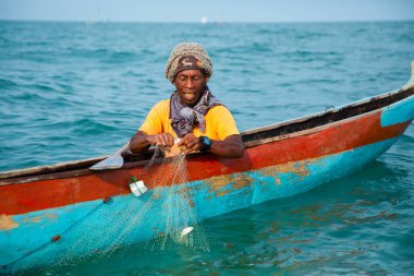 Morondava, Madagaskar. 18 Ekim 2023. Ev yapımı ahşap pirogue teknesindeki kötü niyetli balıkçı ağla balık yakalar. seçici odak, okyanusun yakın görüntüsü