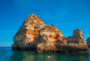 Portekiz 'in Algarve kıyısındaki okyanusta gün batımında şaşırtıcı derecede güzel kayalar. Altın güneş ışınları. Lagos Porugal