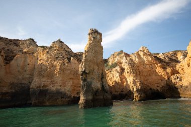Portekiz 'in Algarve kıyısındaki okyanusta gün batımında şaşırtıcı derecede güzel kayalar. Altın güneş ışınları. Lagos Porugal
