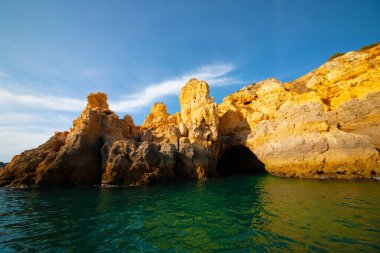 Portekiz 'in Algarve kıyısındaki okyanusta gün batımında şaşırtıcı derecede güzel kayalar. Altın güneş ışınları. Lagos Porugal