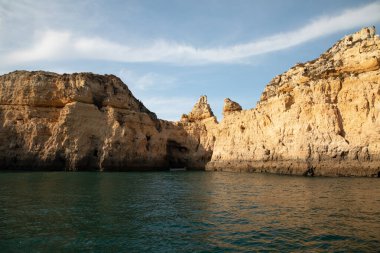 Portekiz 'in Algarve kıyısındaki okyanusta gün batımında şaşırtıcı derecede güzel kayalar. Altın güneş ışınları. Lagos Porugal