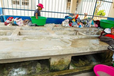 Antananarivo, Madagaskar. 25 Ekim 2023 Antananarivo 'da çamaşır yıkama. Kadının çamaşır yıkadığı lavabolu beton blok. Yıkanmış ıslak giysiler yığını