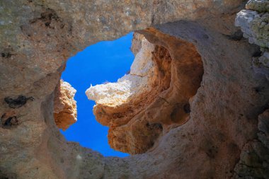 Portekiz 'in Algarve kıyısındaki okyanusta gün batımında şaşırtıcı derecede güzel kayalar. Altın güneş ışınları. Lagos Porugal