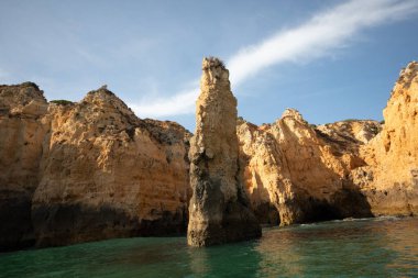 Portekiz 'in Algarve kıyısındaki okyanusta gün batımında şaşırtıcı derecede güzel kayalar. Altın güneş ışınları. Lagos Porugal