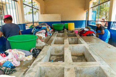 Antananarivo, Madagaskar. 25 Ekim 2023 Antananarivo 'da çamaşır yıkama. Kadının çamaşır yıkadığı lavabolu beton blok. Yıkanmış ıslak giysiler yığını