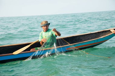 Morondava, Madagaskar. 18 Ekim 2023. Ev yapımı ahşap pirogue teknesindeki kötü niyetli balıkçı ağla balık yakalar. seçici odak, okyanusun yakın görüntüsü