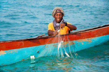 Morondava, Madagaskar. 18 Ekim 2023. Ev yapımı ahşap pirogue teknesindeki kötü niyetli balıkçı ağla balık yakalar. seçici odak, okyanusun yakın görüntüsü