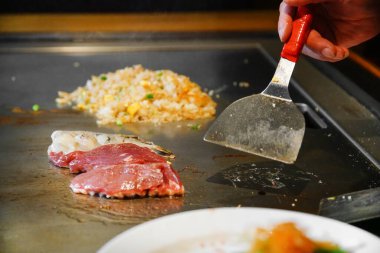 Şefin elleri teppanyaki yerine spatula ile. Sebze pişirmek et ve deniz ürünleri sıcak hibachi ızgara masasında. Geleneksel Japon mutfağı. Teppan gösterisi