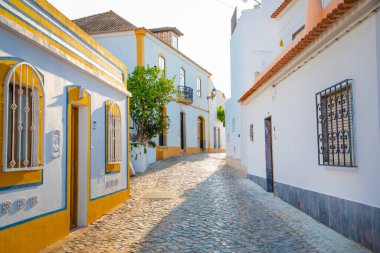 Ferragudo, Algarve, Portekiz. 26 Eylül 2020. Portekiz 'in Ferragudo balıkçı köyündeki Bougainvillea çiçekleriyle süslenmiş dar sokaklardaki kiremitli çatıları olan geleneksel beyaz evler.