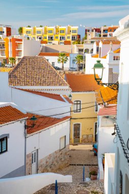 Ferragudo, Algarve, Portekiz. 26 Eylül 2020. Portekiz 'in Ferragudo balıkçı köyündeki Bougainvillea çiçekleriyle süslenmiş dar sokaklardaki kiremitli çatıları olan geleneksel beyaz evler.