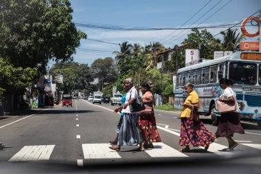 Kalutara, Sri Lanka 09 Şubat 2023. Sri Lankalı renkli elbiseli kadınlar yaya geçidinden karşıya geçiyorlar..