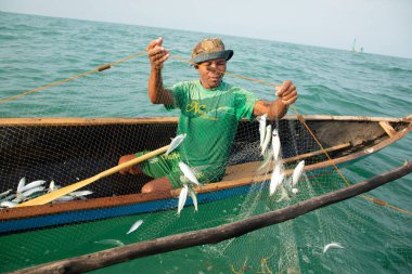 Morondava, Madagaskar. 18 Ekim 2023. Ev yapımı ahşap pirogue teknesindeki kötü niyetli balıkçı ağla balık yakalar. seçici odak, okyanusun yakın görüntüsü