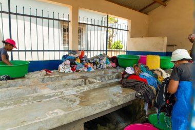 Antananarivo, Madagaskar. 25 Ekim 2023 Antananarivo 'da çamaşır yıkama. Kadının çamaşır yıkadığı lavabolu beton blok. Yıkanmış ıslak giysiler yığını