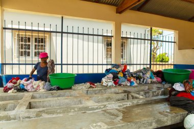 Antananarivo, Madagaskar. 25 Ekim 2023 Antananarivo 'da çamaşır yıkama. Kadının çamaşır yıkadığı lavabolu beton blok. Yıkanmış ıslak giysiler yığını