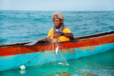 Morondava, Madagaskar. 18 Ekim 2023. Ev yapımı ahşap pirogue teknesindeki kötü niyetli balıkçı ağla balık yakalar. seçici odak, okyanusun yakın görüntüsü