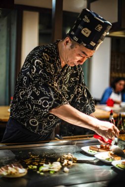 Berlin, Almanya 05. 09 numara. 2019. Teppanyaki şefi bir Japon et lokantasında Teppan 'da yemek pişiriyor. Japon şef ateşli bir gösteri sergiliyor ve alev saçıyor