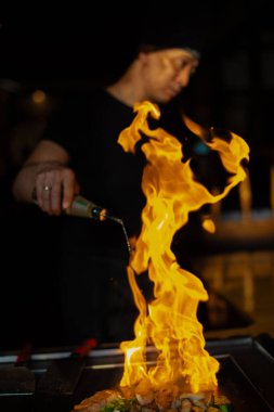 Berlin, Almanya 08.16.2023. Teppanyaki şefi bir Japon et lokantasında Teppan 'da yemek pişiriyor. Japon şef ateşli bir gösteri sergiliyor ve alev saçıyor