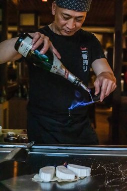 Berlin, Almanya 08. 16 yaşında. 2023. Teppanyaki şefi bir Japon et lokantasında Teppan 'da yemek pişiriyor. Japon şef ateşli bir gösteri sergiliyor ve alev saçıyor