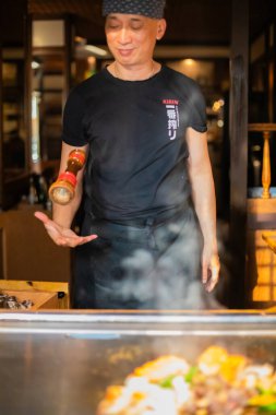 Berlin, Almanya 08.16.2023. Teppanyaki şefi bir Japon et lokantasında Teppan 'da yemek pişiriyor. Japon şef ateşli bir gösteri sergiliyor ve alev saçıyor