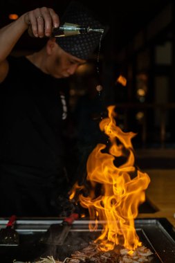 Berlin, Almanya 08.16.2023. Teppanyaki şefi bir Japon et lokantasında Teppan 'da yemek pişiriyor. Japon şef ateşli bir gösteri sergiliyor ve alev saçıyor