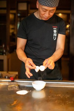 Berlin, Almanya 08.16.2023. Teppanyaki şefi bir Japon et lokantasında Teppan 'da yemek pişiriyor. Japon şef ateşli bir gösteri sergiliyor ve alev saçıyor