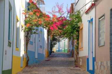 Ferragudo, Algarve, Portekiz. 26 Eylül 2020. Portekiz 'in Ferragudo balıkçı köyündeki Bougainvillea çiçekleriyle süslenmiş dar sokaklardaki kiremitli çatıları olan geleneksel beyaz evler.