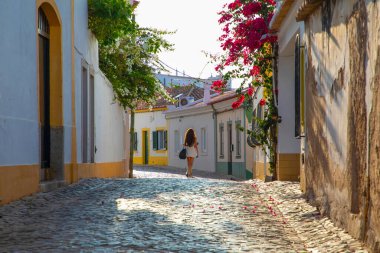 Ferragudo, Algarve, Portekiz. 26 Eylül 2020. Portekiz 'in Ferragudo balıkçı köyündeki Bougainvillea çiçekleriyle süslenmiş dar sokaklardaki kiremitli çatıları olan geleneksel beyaz evler.