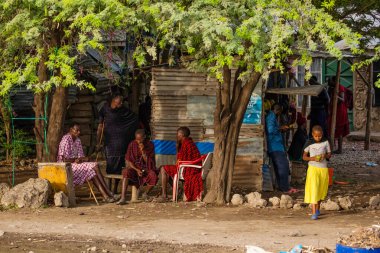 Arusha, Tanzanya, Afrika. 3 Şubat 2022 'de Afrika köyünde yaşam. Afrika seyahati Geleneksel giysiler içinde Masai erkekleri evin yanındaki sandalyelere otururlar.