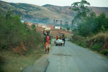 Madagaskar, 19 Ekim 2023. Madagaskar yolları. Çeşitli Malagasy 'li insanlar sabahın erken saatlerinde tozlu bir yolda yürürler.