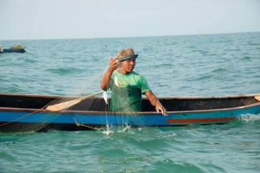 Morondava, Madagaskar. 18 Ekim 2023. Ev yapımı ahşap pirogue teknesindeki kötü niyetli balıkçı ağla balık yakalar. seçici odak, okyanusun yakın görüntüsü
