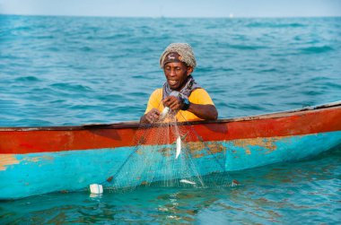 Morondava, Madagaskar. 18 Ekim 2023. Ev yapımı ahşap pirogue teknesindeki kötü niyetli balıkçı ağla balık yakalar. seçici odak, okyanusun yakın görüntüsü