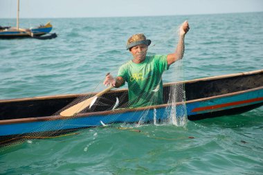 Morondava, Madagaskar. 18 Ekim 2023. Ev yapımı ahşap pirogue teknesindeki kötü niyetli balıkçı ağla balık yakalar. seçici odak, okyanusun yakın görüntüsü