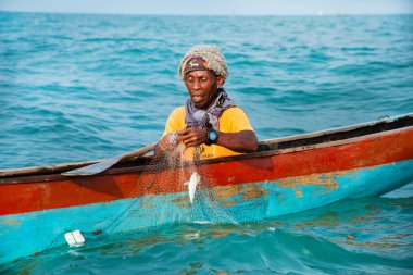 Morondava, Madagaskar. 18 Ekim 2023. Ev yapımı ahşap pirogue teknesindeki kötü niyetli balıkçı ağla balık yakalar. seçici odak, okyanusun yakın görüntüsü