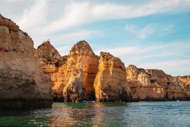 Portekiz 'in Algarve kıyısındaki okyanusta gün batımında şaşırtıcı derecede güzel kayalar. Altın güneş ışınları. Lagos Porugal