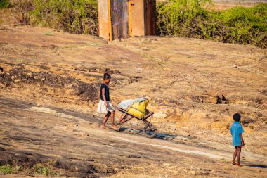 Antsirabe, Madagaskar. 19 Ekim 2023. Madagaskar. Üç küçük çocuk, çuval dolu bir arabayı tepeye itiyor.