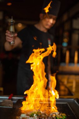 Berlin, Almanya 08. 16 yaşında. 2023. Teppanyaki şefi bir Japon et lokantasında Teppan 'da yemek pişiriyor. Japon şef ateşli bir gösteri sergiliyor ve alev saçıyor