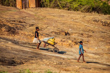 Antsirabe, Madagaskar. 19 Ekim 2023. Madagaskar. Üç küçük çocuk, çuval dolu bir arabayı tepeye itiyor.