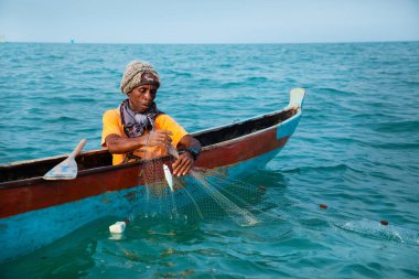 Morondava, Madagaskar. 18 Ekim 2023. Ev yapımı ahşap pirogue teknesindeki kötü niyetli balıkçı ağla balık yakalar. seçici odak, okyanusun yakın görüntüsü