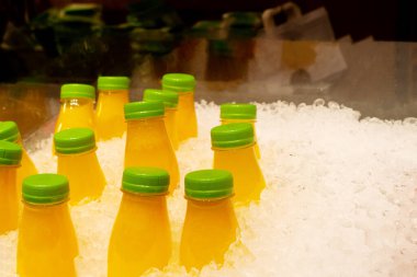 Buzlu taze meyve suyu. Birkaç plastik meyve suyu standı buzda soğutuluyor, satışa hazır.