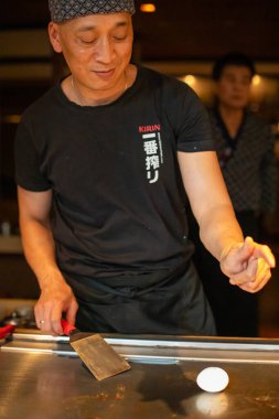 Berlin, Almanya 08. 16 yaşında. 2023. Teppanyaki şefi bir Japon et lokantasında Teppan 'da yemek pişiriyor. Japon şef ateşli bir gösteri sergiliyor ve alev saçıyor