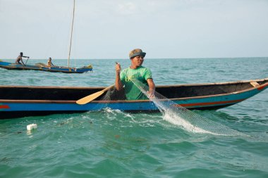 Morondava, Madagaskar. 18 Ekim 2023. Ev yapımı ahşap pirogue teknesindeki kötü niyetli balıkçı ağla balık yakalar. seçici odak, okyanusun yakın görüntüsü