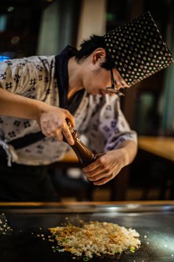 Berlin, Almanya 05. 09 numara. 2019. Teppanyaki şefi bir Japon et lokantasında Teppan 'da yemek pişiriyor. Japon şef ateşli bir gösteri sunuyor.