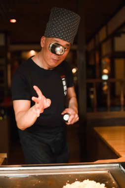 Berlin, Almanya 08. 16 yaşında. 2023. Teppanyaki şefi bir Japon et lokantasında Teppan 'da yemek pişiriyor. Japon şef ateşli bir gösteri sergiliyor ve alev saçıyor
