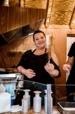 Leipzig, Almanya. 09.06. 2019. Genç, iri yarı, gülümseyen ve elinde patates sarmalı tornado cipsleri tutan bir kadın.