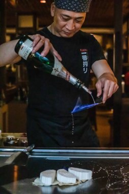 Berlin, Almanya 08. 16 yaşında. 2023. Teppanyaki şefi bir Japon et lokantasında Teppan 'da yemek pişiriyor. Japon şef ateşli bir gösteri sergiliyor ve alev saçıyor
