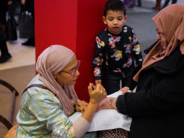 Berlin, Almanya 20.01. 2023 Mehndi ustası kadın eline kına dövmesi çiziyor, mehendi sanat.