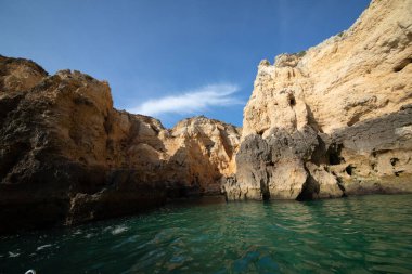 Portekiz 'in Algarve kıyısındaki okyanusta gün batımında şaşırtıcı derecede güzel kayalar. Altın güneş ışınları. Lagos Porugal. Yaz doğası.