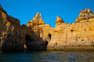 Portekiz 'in Algarve kıyısındaki okyanusta gün batımında şaşırtıcı derecede güzel kayalar. Altın güneş ışınları. Lagos Porugal